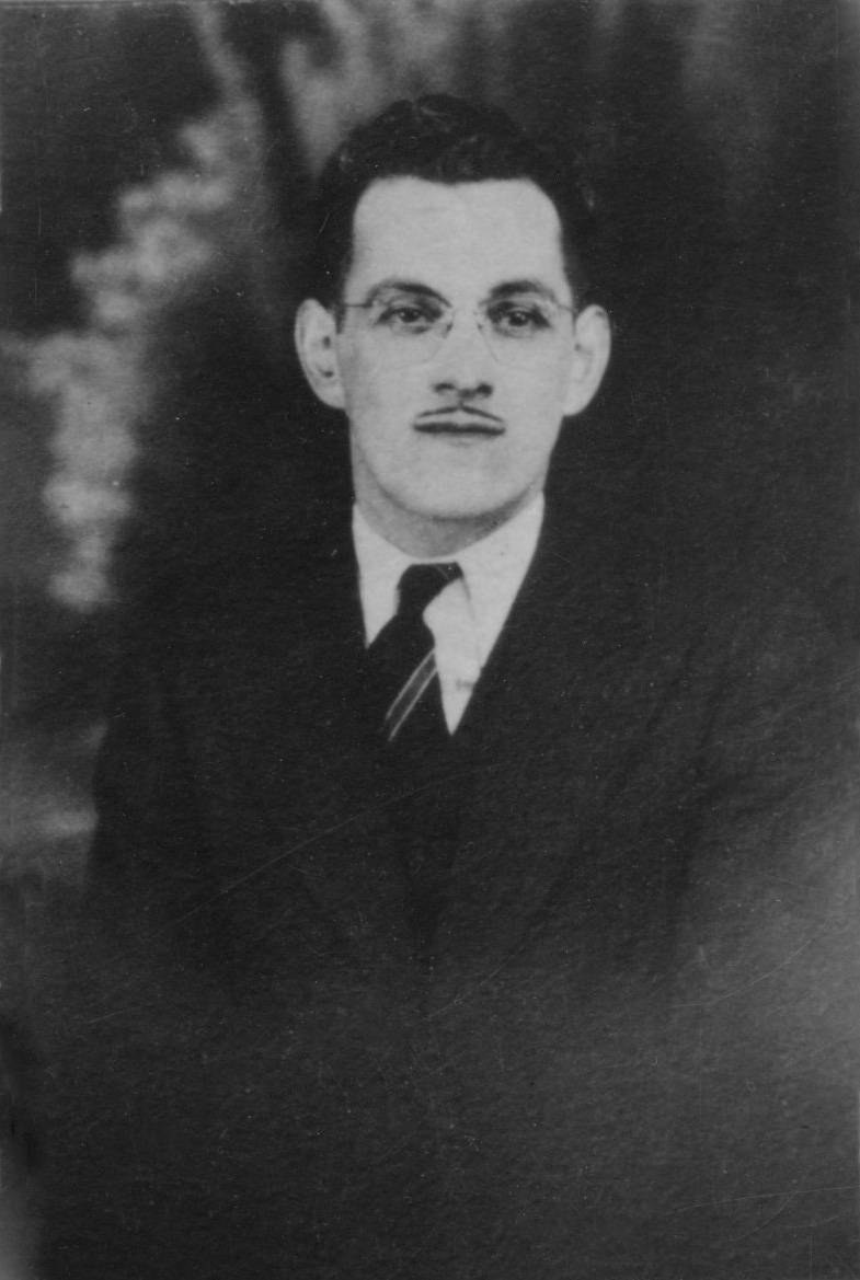 Photographie en noir et blanc, portrait de Léopold Bombardier. M. Bombardier porte la moustache, des lunettes, un veston, une chemise blanche et une cravate rayée.